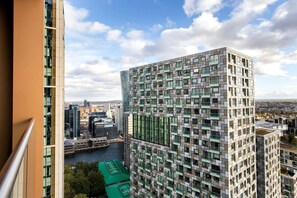 Un immeuble moderne de grande hauteur, doté d’une façade à motifs géométriques, de grandes fenêtres et offrant une vue sur une rivière et le paysage urbain.