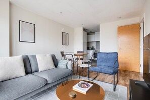 Un salon moderne avec un canapé gris, un fauteuil bleu et une table basse sur laquelle repose un livre.