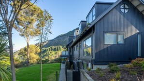 A modern two-story house with a covered walkway, surrounded by a well-maintained lawn and trees. - Arawata Alpine Views - 2BDRM luxury (Queenstown)