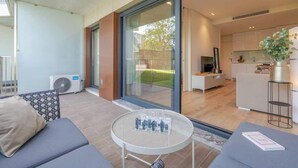 Een moderne woonkamer met een bank, een ronde tafel en een keuken op de achtergrond.