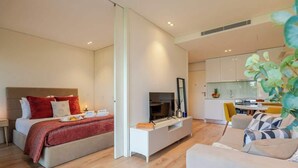 Een moderne hotelkamer met een bed, een televisie, een eethoek en een keuken.