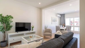 Un salon moderne doté d’un téléviseur à écran plat, d’un canapé, d’une table basse et d’un coin repas avec une table et des chaises.