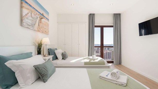 Une chambre d’hôtel avec un lit, une télévision, un balcon et un tableau au mur.