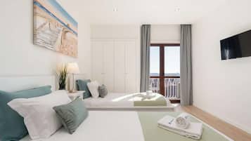A hotel room with a bed, a TV, a balcony, and a painting on the wall.