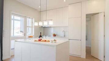 A modern kitchen with white cabinetry, a central island with a glass-top, and pendant lighting.