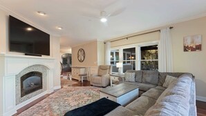 A living room with a fireplace, a large flat-screen TV, a sofa, and a coffee table. - Lake Norman Retreat w/ Pool, Hot Tub & Private Dock Lake Life Cove by Avantstay (Mooresville)