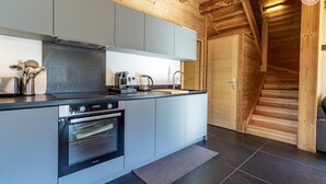 A modern kitchen with grey cabinets, a built-in oven, and a coffee maker. - MAKALU LODGE - BEAUFORT (BEAUFORT)