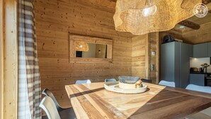 A wooden interior with a dining table, chairs, a woven light fixture, and a kitchen area. - MAKALU LODGE - BEAUFORT (BEAUFORT)