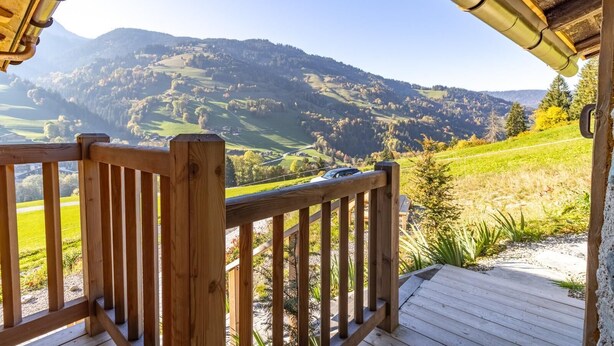 A wooden deck with a view of rolling hills and a car parked in the distance. - MAKALU LODGE - BEAUFORT (BEAUFORT)