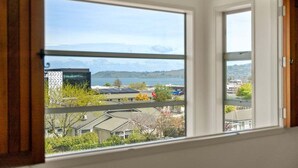 Ett rum med ett stort fönster med utsikt över en vattenyta och byggnader.