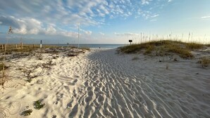 Een zandstrand met weinig begroeiing en een heldere lucht.