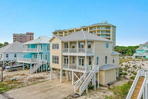 A beachfront property with multiple buildings, including a two-story house with a balcony and a larger building with multiple balconies. - Steps to Beach | Community Pool & Hot Tub | Spacious Family Retreat | BEACHBALL PROPERTIES (Gulf Shores)