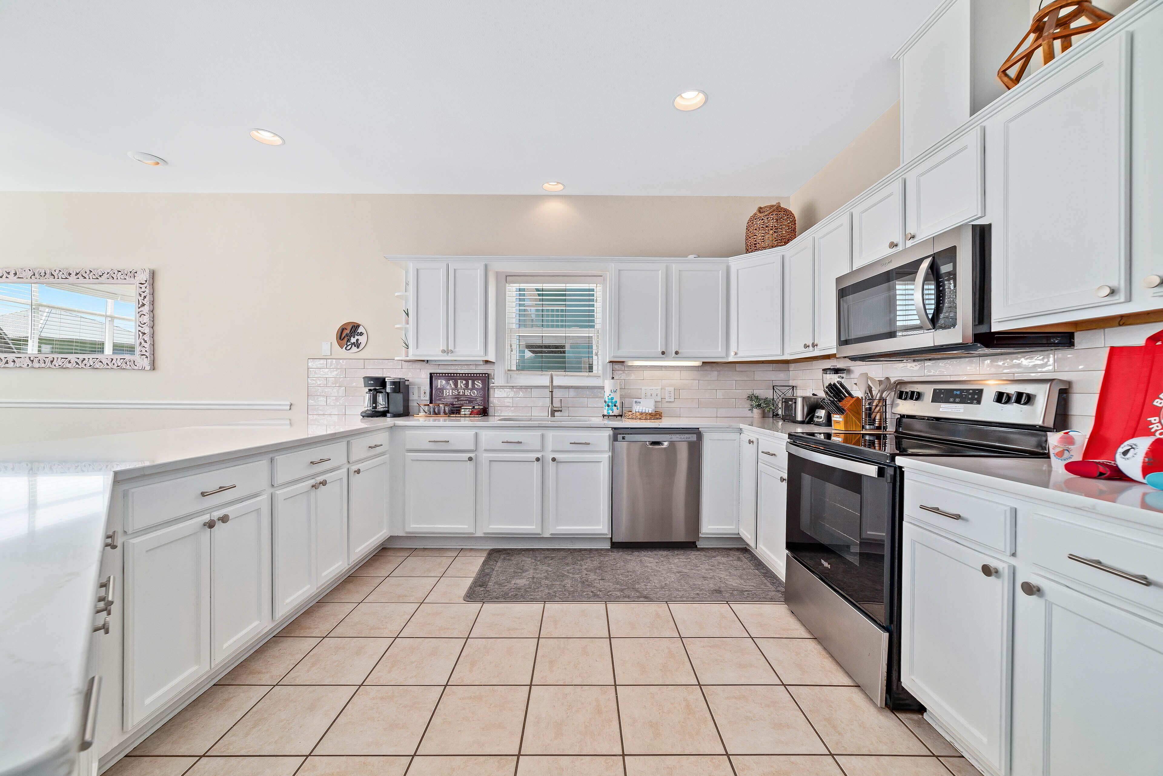 A modern kitchen with white cabinetry, a dishwasher, a stove, and a microwave.