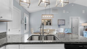 Una cocina moderna con encimeras de granito, electrodomésticos de acero inoxidable e iluminación colgante.