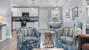 Una cocina moderna con armarios blancos, electrodomésticos de acero inoxidable y una zona de comedor con mesa y sillas.