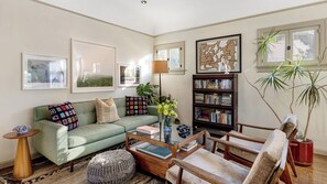 A living room with a green sofa, a coffee table, a bookshelf, and a potted plant. - Spanish Revival Charm in Silver Lake w/ Patio, BBQ & Walkable Location Maltman Manor by Avantstay (Los Angeles)