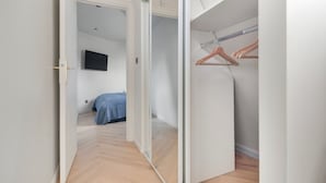 Un dormitorio con una cama, un televisor montado en la pared y un armario con barra de madera.