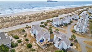 Zona residencial costera con casas de tejados a dos aguas y una playa al fondo.