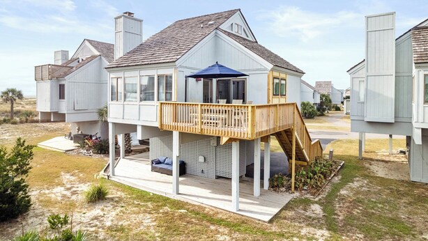 Una casa frente al mar con terraza de madera y un pequeño espacio exterior para sentarse.
