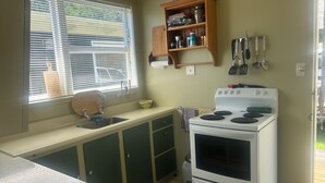 Una cocina compacta con un lavamanos, estufa y ventana con persianas.