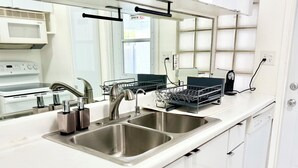Una cocina moderna con lavamanos de acero inoxidable, un escurreplatos y un microondas.
