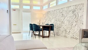 Una sala de estar moderna con una mesa de centro de vidrio, sillas color turquesa y un sofá blanco.