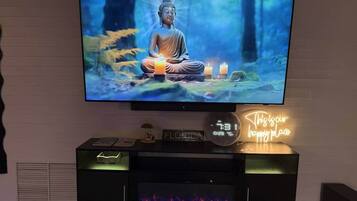 Un televisor montado en la pared que muestra una estatua de Buda, un reloj y un letrero de neón.