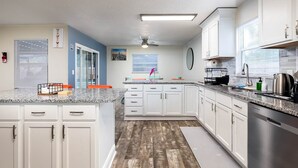 A modern kitchen with white cabinets, granite countertops, and a wooden floor. - Serene Sunshine State Escape (Deltona)