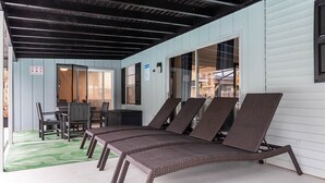 A covered patio with wicker lounge chairs, a table, and chairs. - Serene Sunshine State Escape (Deltona)