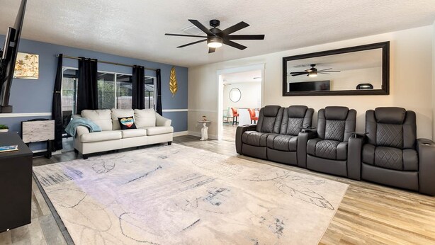 A living room with a white sofa, a black leather sofa, a ceiling fan, and a large mirror on the wall. - Serene Sunshine State Escape (Deltona)