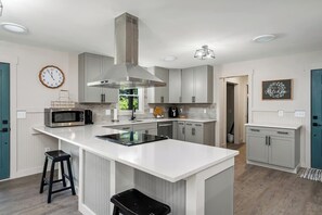 Uma cozinha moderna com uma ilha central, eletrodomésticos de aço inoxidável e armários em tons claros.