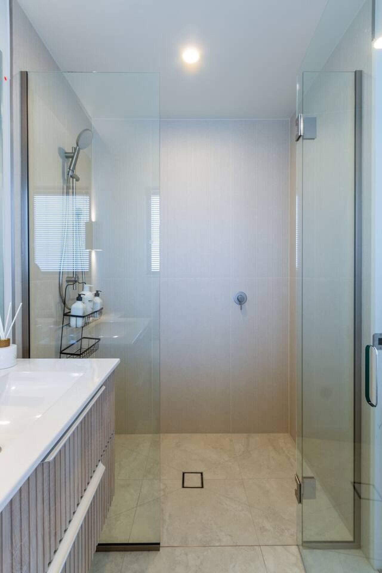 A modern bathroom with a glass shower enclosure, a white sink with a mirror, and a towel rack.