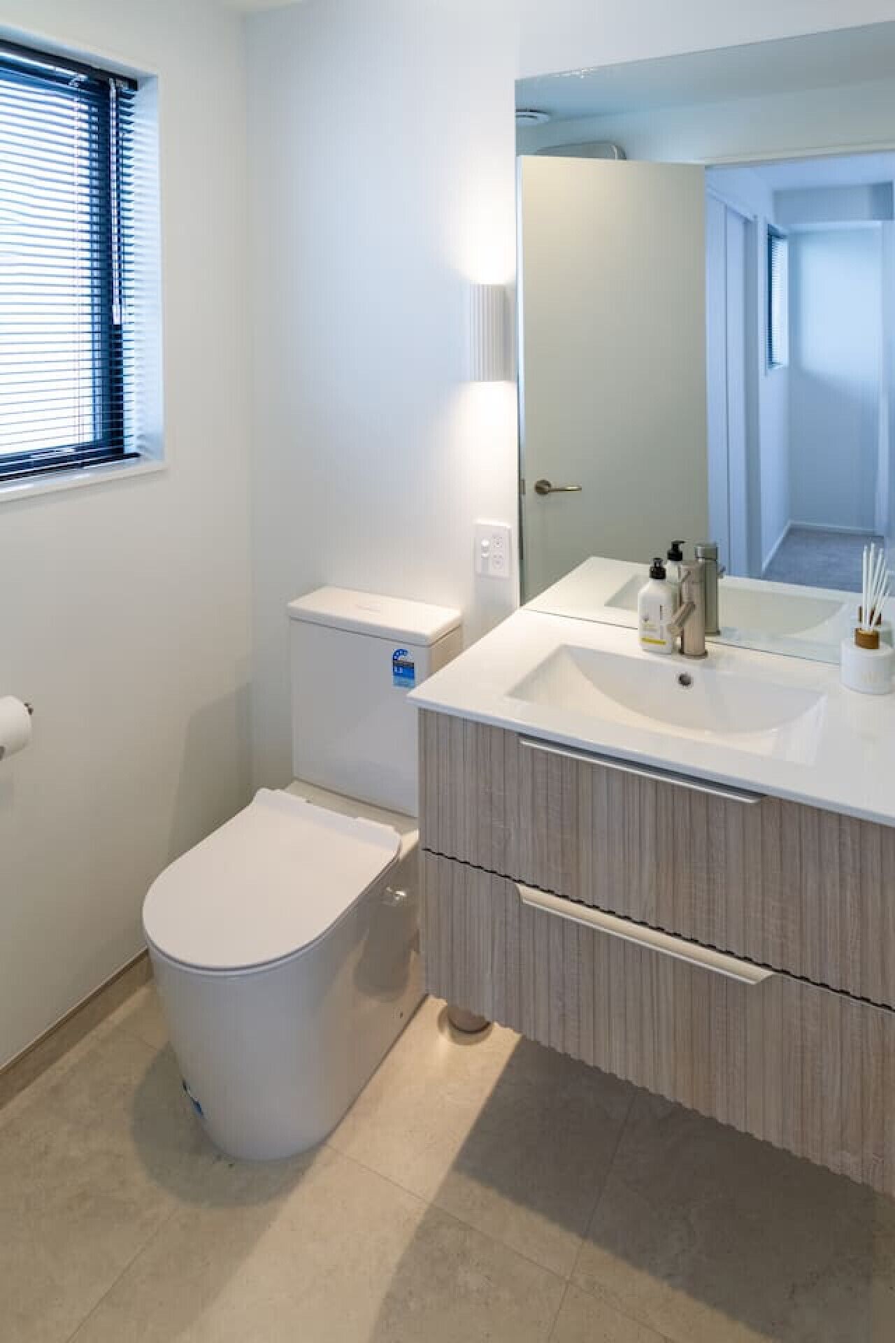 A modern bathroom with a toilet, sink, and mirror.