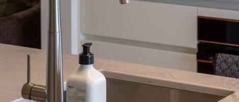 A modern kitchen with a stainless steel faucet, a coffee maker, and a bottle of hand soap on the counter.