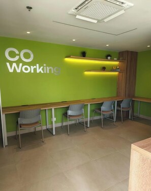 A modern office space with a green wall, a long wooden table, and four chairs. - Suite vacacional (Cartagena)