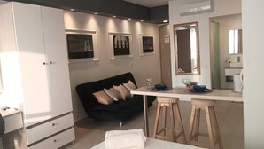 Een moderne kamer met een zwarte bank, een wit bureau en een spiegel.