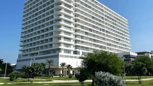 Een hotel met meerdere verdiepingen, een gelijkmatig uiterlijk, balkons op elke verdieping en een plat dak.