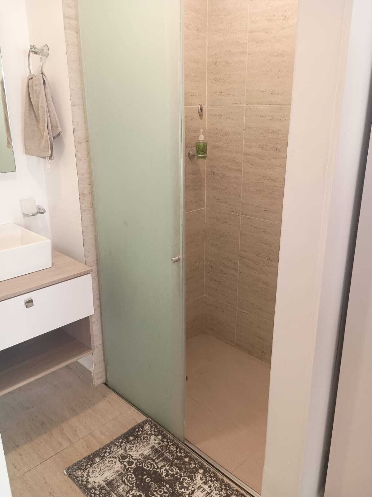 Un baño con ducha, lavamanos y espejo.