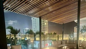 Een moderne, open loungeruimte met een houten plafond, comfortabele zitplaatsen en uitzicht op de stad.