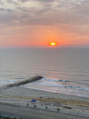 A sunset over a beach with a rocky outcrop and a clear sky. - Suite vacacional (Cartagena)