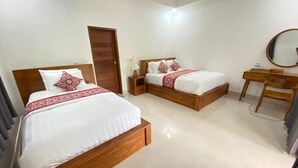 Una habitación de hotel con dos camas de madera, un escritorio de madera, un espejo y una puerta.
