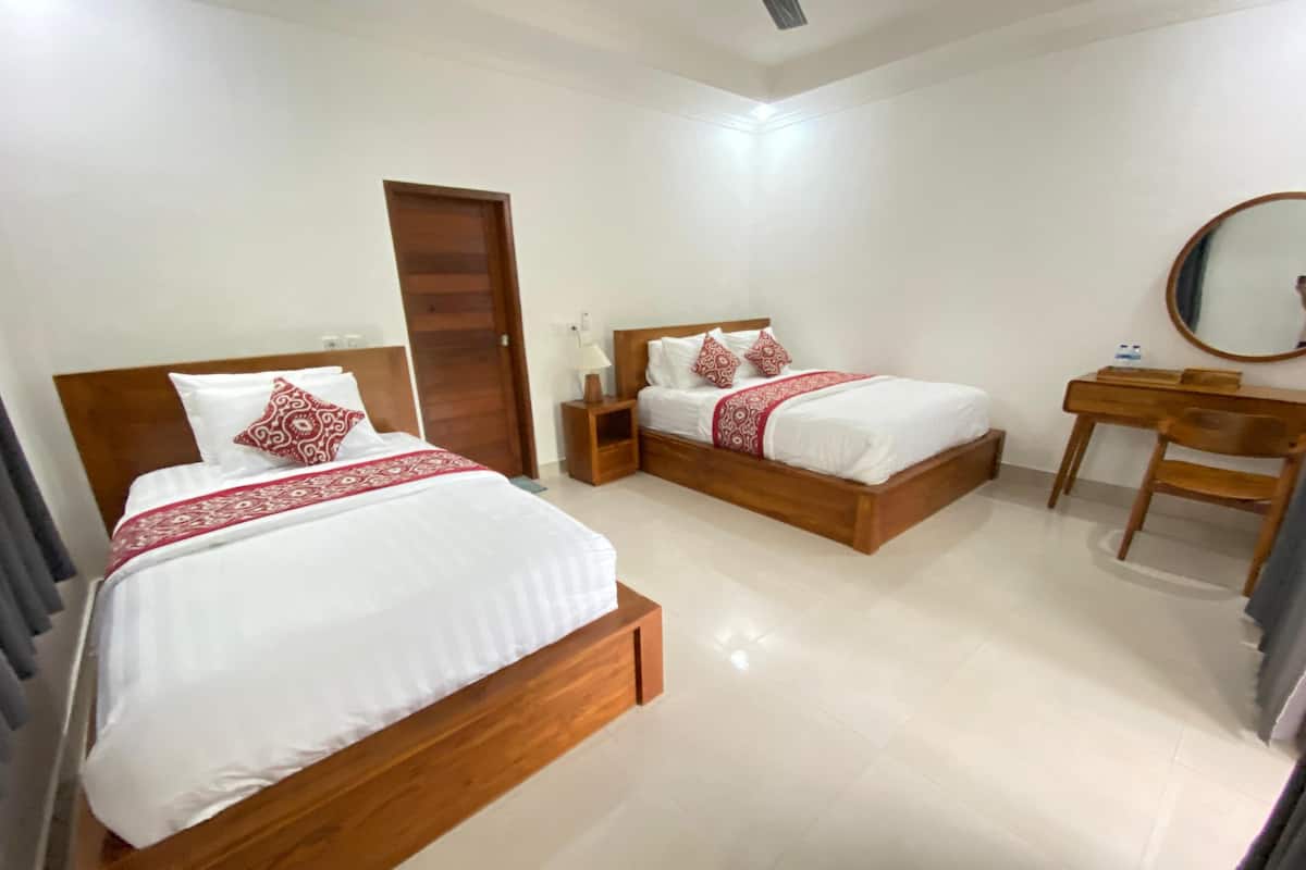 A hotel room with two wooden beds, a wooden desk, a mirror, and a door.
