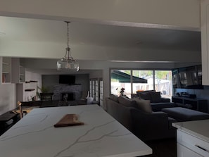 Un espacio habitable moderno con una isla de cocina, zona de estar y chimenea.