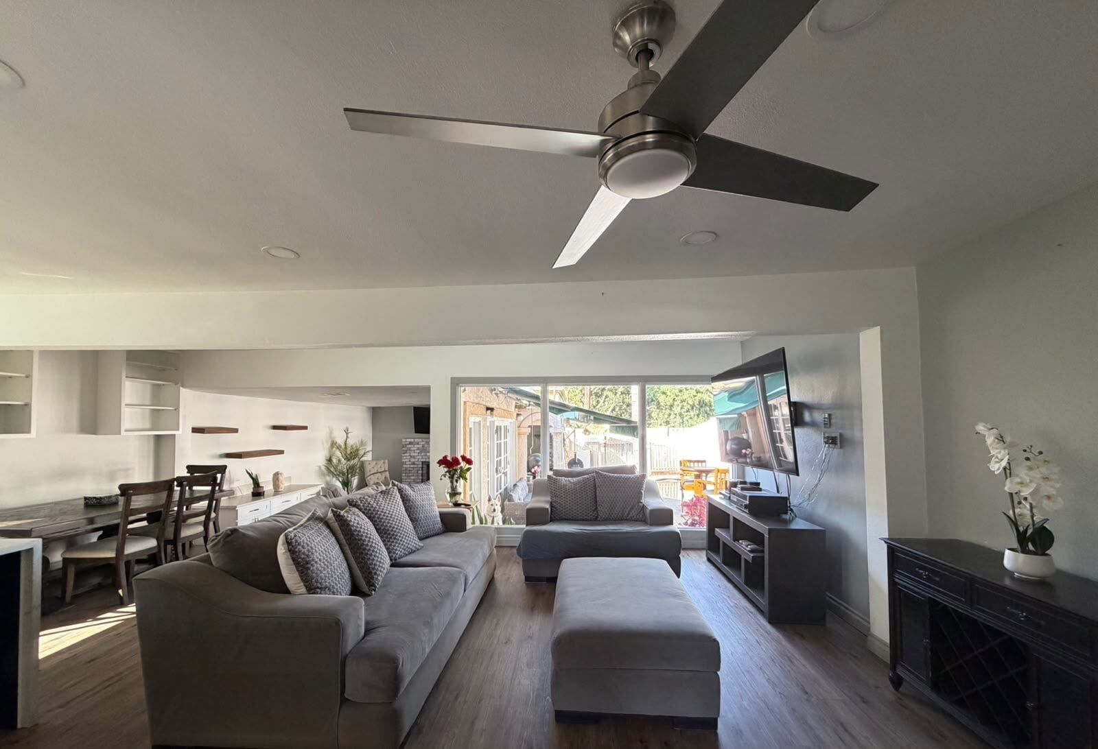 A modern living room with a sofa, ottoman, and a ceiling fan.