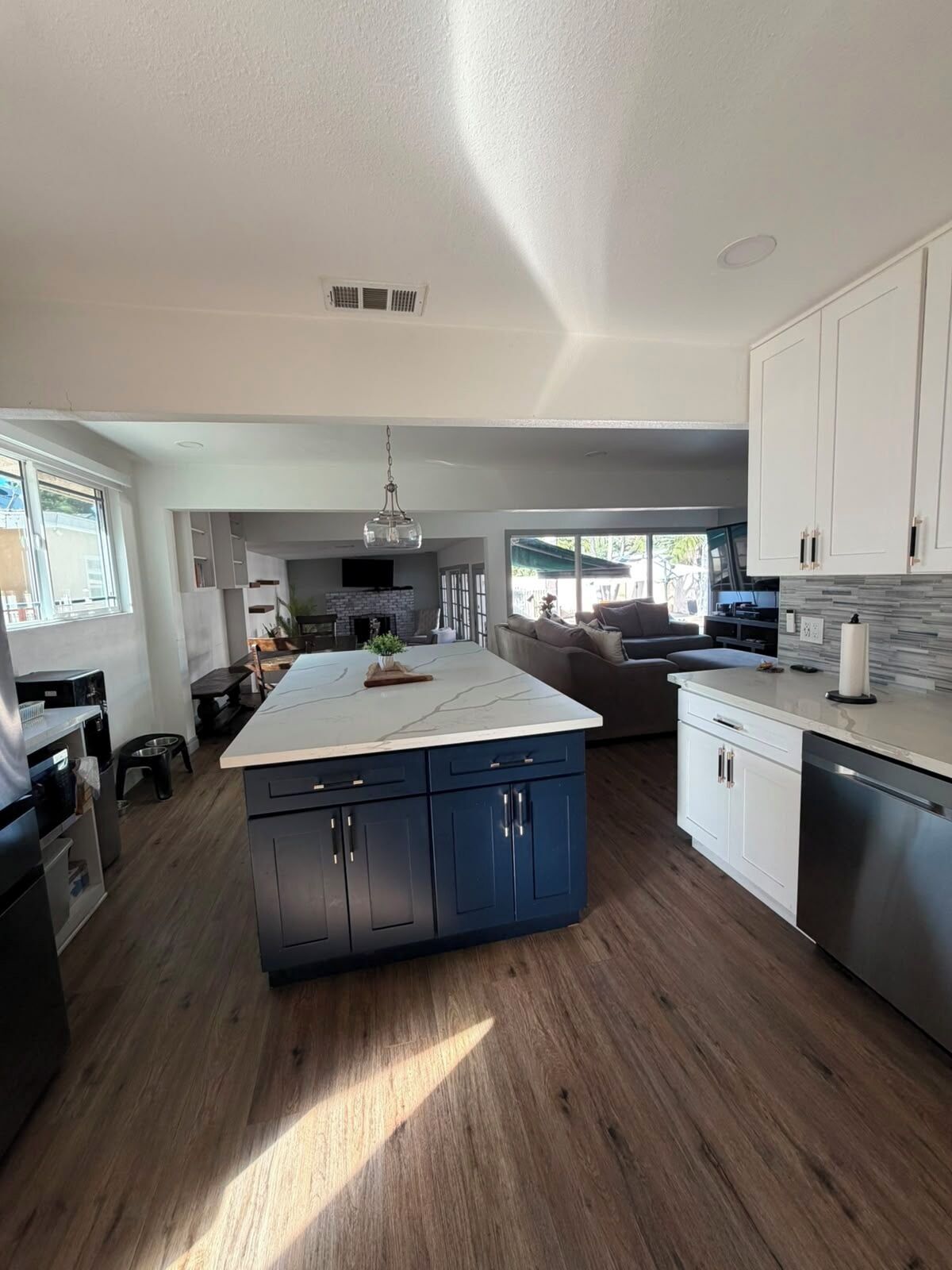 A modern kitchen with a central island, built-in cabinets, and a dining area with a sofa.