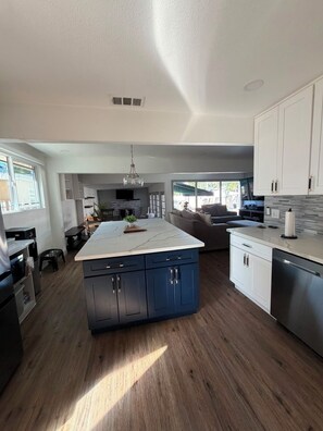 A modern kitchen with a central island, built-in cabinets, and a dining area with a sofa.