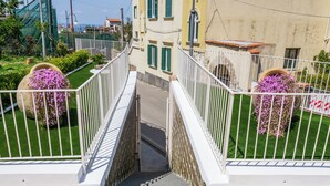 Una escalera conduce a un balcón con barandas blancas y plantas en macetas.