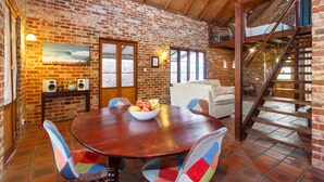 Un comedor rústico con una mesa de madera, sillas coloridas y un cuenco de fruta.