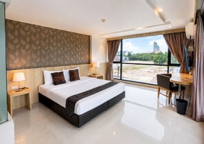 A modern hotel room with a large bed, a desk, and a view of the cityscape. - Arawana Regency South Pattaya (Pattaya)