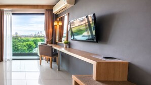 Une chambre d’hôtel moderne dotée d’une grande fenêtre, d’un téléviseur à écran plat fixé au mur, d’un bureau en bois et d’une chaise.